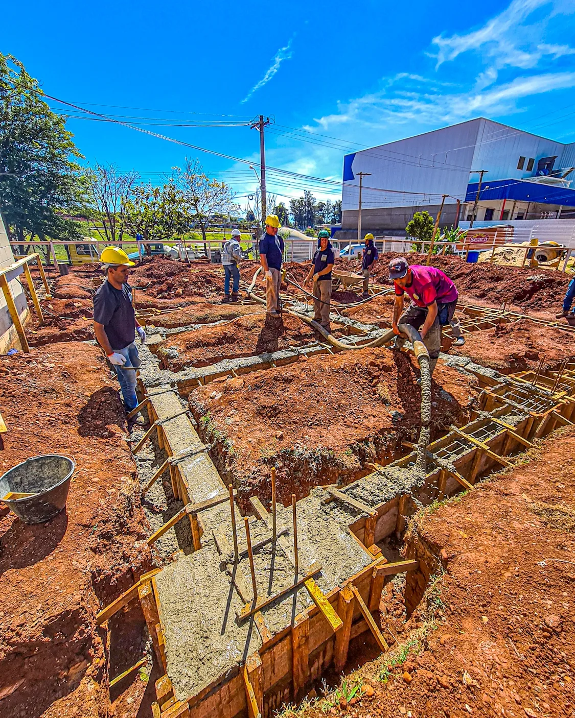 Equipe de obra realizando a concretagem das vigas de fundação com mangote